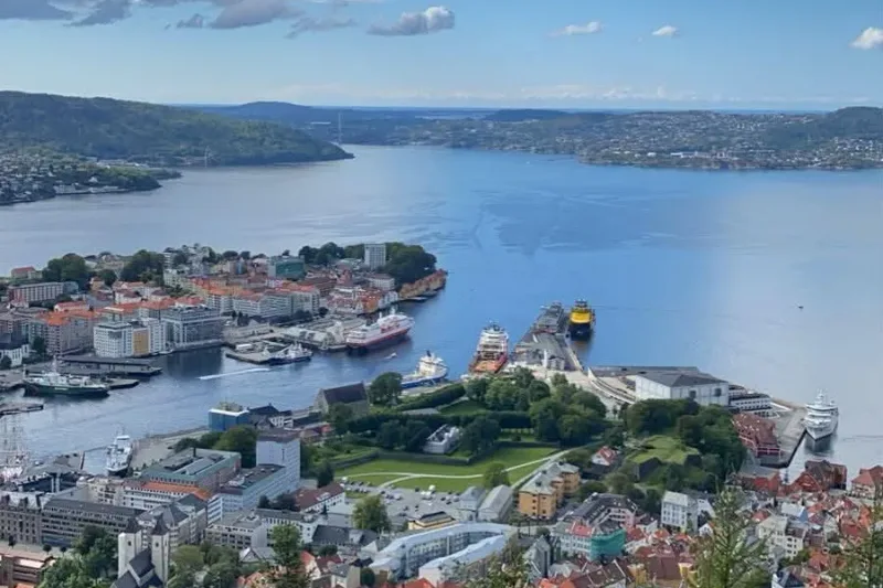 Bergen harbour and the Bryggen wharf seen from the Fløyen hillside on a clear summer day, boats moored along the quay.